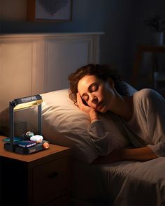 a woman laying in bed with her head on the pillow next to an electronic projector