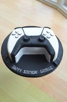 a black and white cake with a video game controller on it's side that says happy birthday george