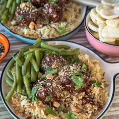 three plates filled with different types of food on top of a striped table cloth next to bowls of crackers and dips