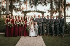 a group of people standing next to each other in front of trees and flowers on the grass