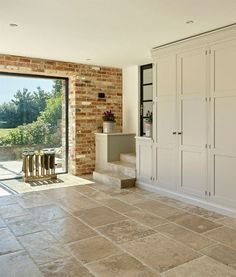 a kitchen with white cabinets and brown tile flooring next to a sliding glass door