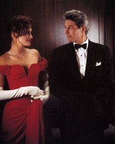 a man in a tuxedo standing next to a woman in a red dress