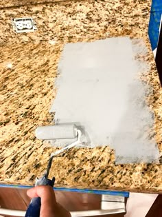 a person using a paint roller on a granite counter top