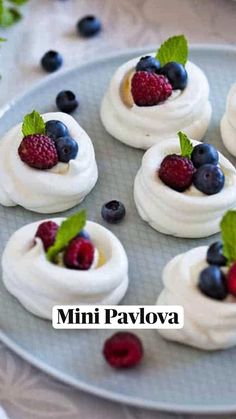 mini pavlovas with berries and mint leaves on a plate