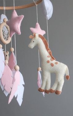 a baby mobile with pink, white and brown toys hanging from it's sides