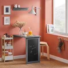 a small chalkboard table in the corner of a room with pink walls and wooden stools