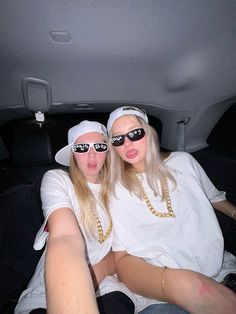 two women sitting in the back of a car with sunglasses on their faces and one woman's legs crossed