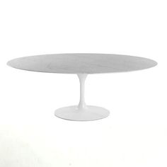 an oval white table with a marble top on a white background in front of a wall