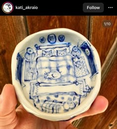 a hand holding a blue and white bowl with an image of a bed on it