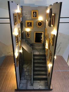 an entry way with stairs and pictures on the wall above it is lit up by lights