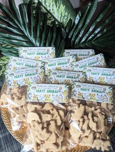 five bags of party animal crackers sitting on top of a plate next to a plant