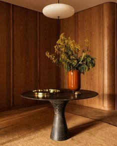 a vase with flowers sitting on top of a table in front of wooden paneled walls