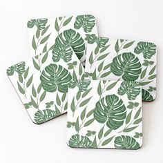 three coasters with green leaves on them sitting next to each other in front of a white background