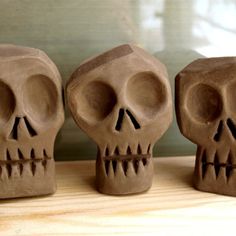 three clay skulls sitting on top of a wooden table