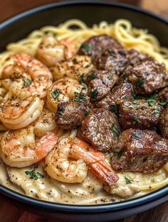 pasta with shrimp, meat and sauce in a black bowl on a wooden table top