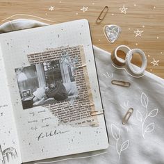 an open book on a table with paper clips, scissors and other items around it