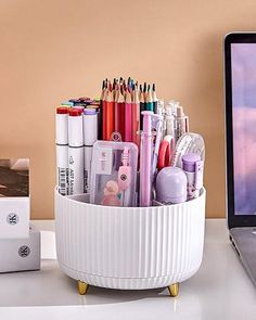 a desk with a laptop and various pens, pencils and markers in a cup