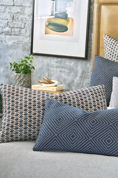 a bed with blue and white pillows on top of it next to a framed photograph