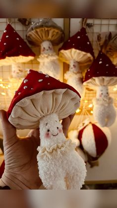 a person holding up a stuffed animal in front of christmas lights and mushrooms hanging from the ceiling