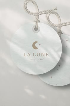 two white tags with the word la lune on them hanging from twine strings