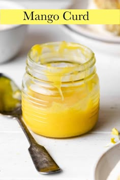 a jar filled with mango curd sitting on top of a table next to a spoon