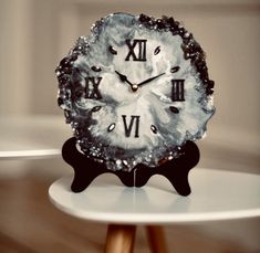 a clock with roman numerals on it sitting on top of a white table