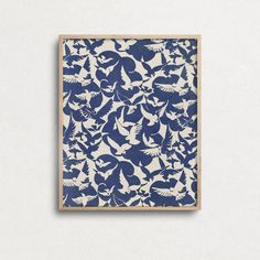 a blue and white print with birds on it in a wooden frame against a wall