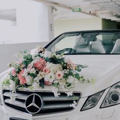 a bouquet of flowers is placed on the hood of a white mercedes benz s - class