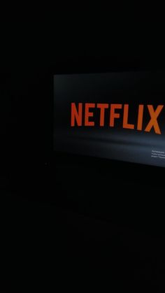 the netflix logo is lit up in the dark with orange letters on it's side