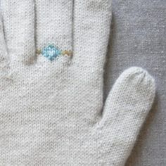 a pair of white knitted gloves sitting on top of a table