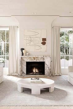 a living room with white furniture and a fire place in the middle of the room