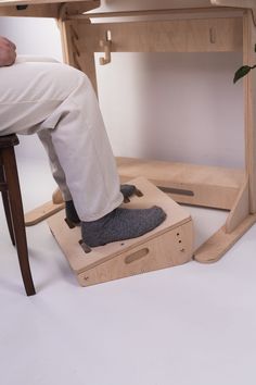 a person sitting on top of a wooden chair with their feet in the bottom half