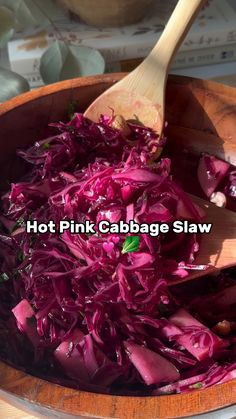 red cabbage is being cooked in a wooden bowl with a spoon on the side and text hot pink cabbage slaw