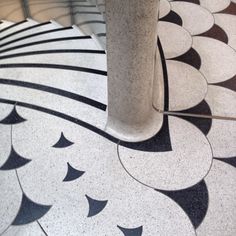 a marble floor with black and white designs on it's sides, next to a tall pillar