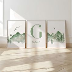 three green watercolor mountains with the letter g on them in front of a white wall