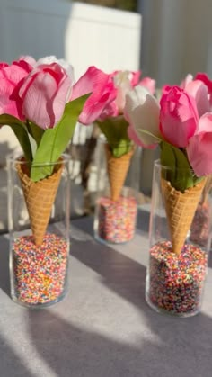 three vases filled with pink flowers and sprinkles on top of a table