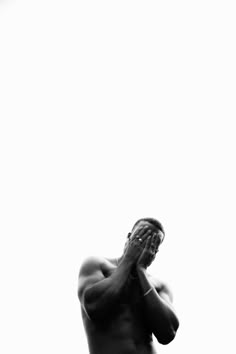 a black and white photo of a man holding his hands up to his face in prayer