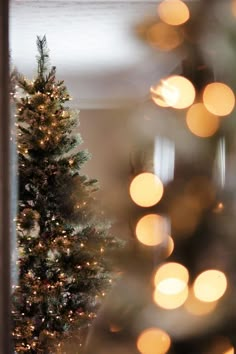 a lit christmas tree in front of a mirror