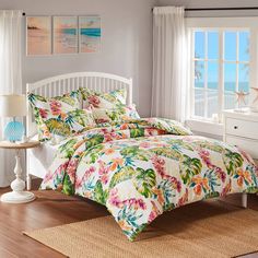 a bed in a bedroom with flowers on the comforter and matching pillowcases