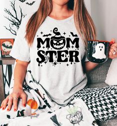 a woman sitting on a couch holding a mug with the word mom ster printed on it