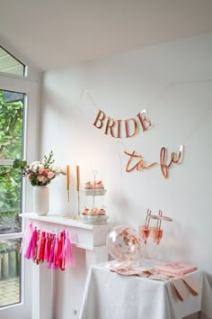 a white table topped with pink tassels next to a window filled with flowers