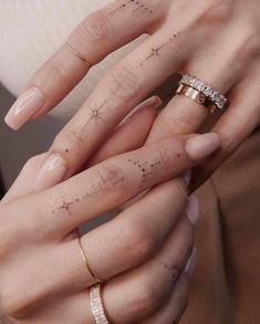 two hands holding each other with tattoos on their fingers