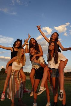 a group of young women standing next to each other on top of a grass covered field