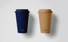 two coffee cups sitting next to each other on a white surface, one is blue and the other is brown