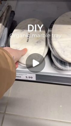 a person is touching some marble plates on a shelf in a store display case with the text diy organic marble trays