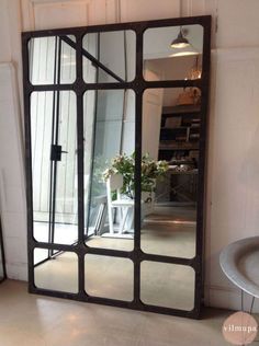 a large mirror sitting on top of a floor next to a vase filled with flowers