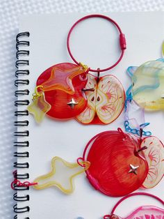 four different colored apple shaped ornaments on a spiral notebook