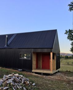 a small black building with a red door