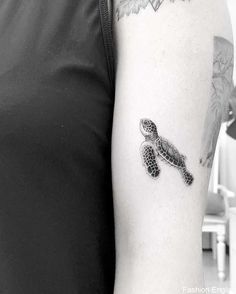 a black and white photo of a woman's arm with a turtle tattoo on it