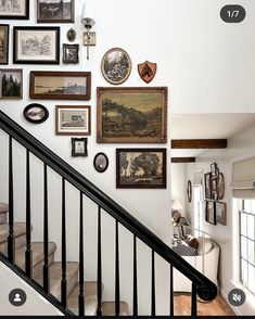 there are many framed pictures on the wall next to the stair case in this house